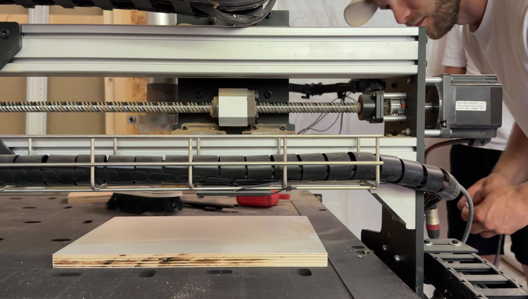 Close view of the CNC gantry and a plywood panel on the workshop table
